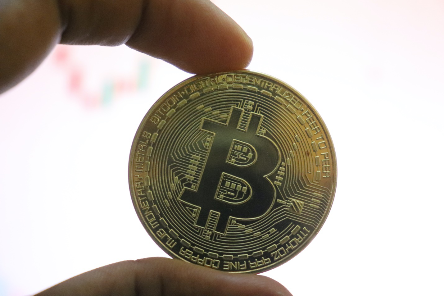 a man holding a gold bitcoin in his hand