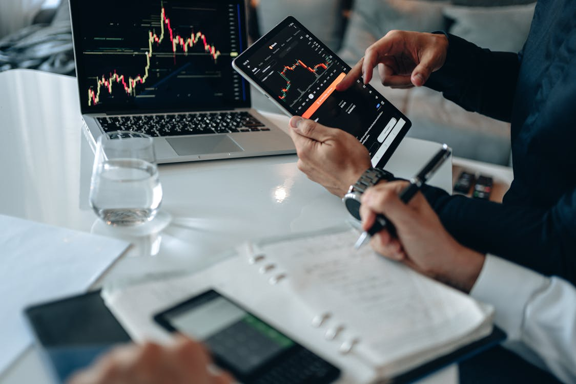 kenson Investments | Future Market Trends: The Rise of Real-World Asset Tokenization and Global Digital Asset Adoption Two cryptocurrency investment consultants analyzing real-world asset tokenization trends on a tablet and laptop.