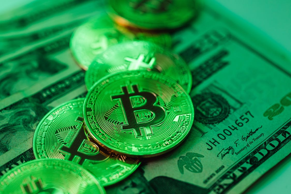 kenson Investments | Future Market Trends: The Rise of Real-World Asset Tokenization and Global Digital Asset Adoption itcoin coins stacked on top of US dollar bills.