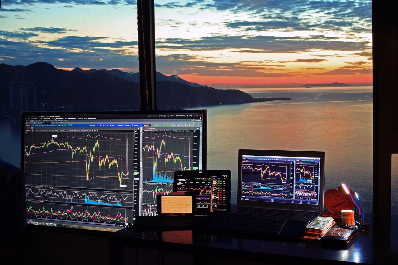 kenson Investments | Future Market Trends: The Rise of Real-World Asset Tokenization and Global Digital Asset Adoption Multiple screens displaying financial charts and data with a scenic sunset view in the background.
