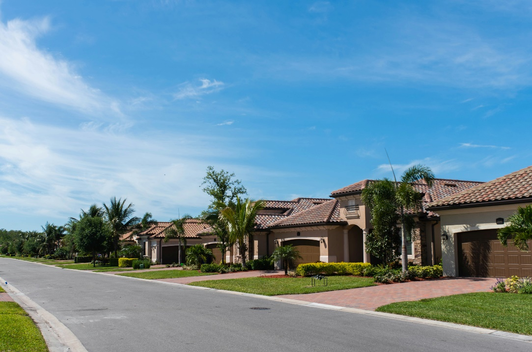 A row of houses with red tile roofs and palm trees.