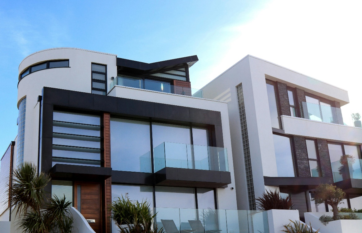 A modern, multi-level luxury home with large windows and a glass balcony