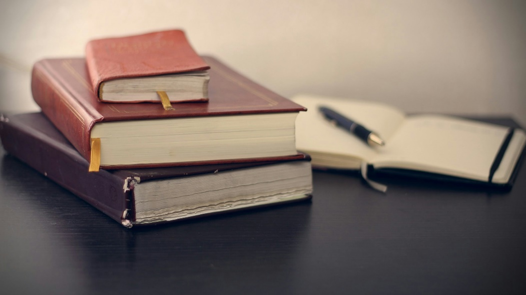 A stack of three books with a red book on top.