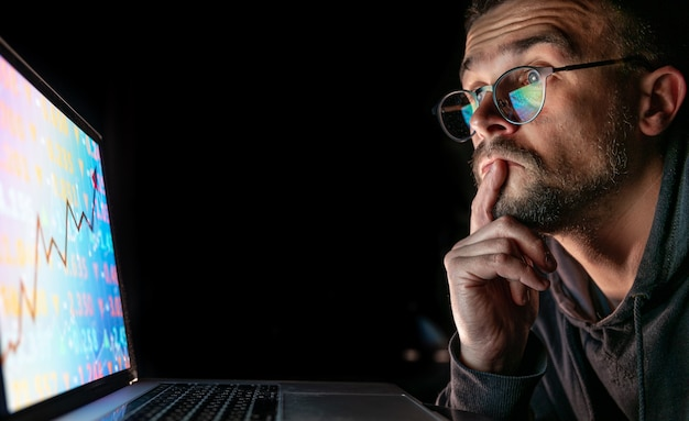 A man studying cryptocurrency investment charts on a laptop
