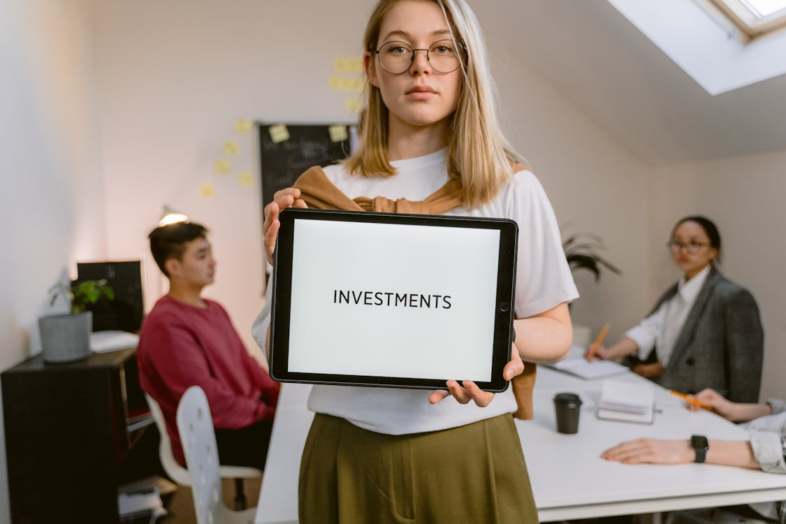 Serious face woman holding a tablet computer with a word "investments" on the screen.