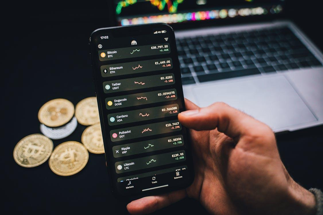 person holding a smartphone with trading graphs