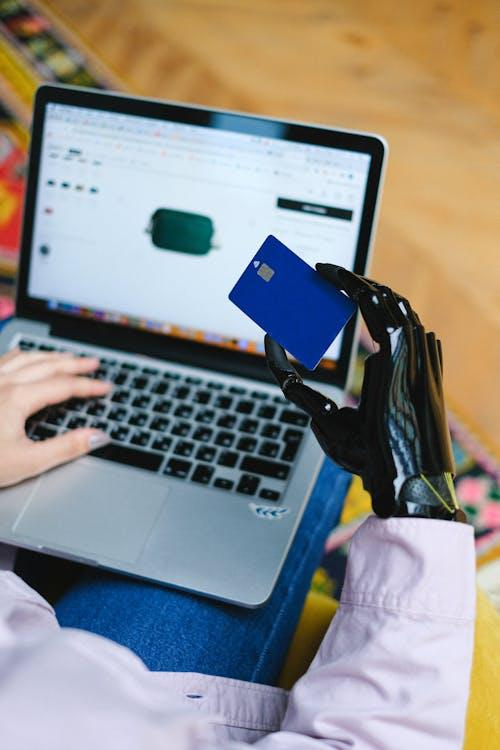 person holding blue card on macbook pro