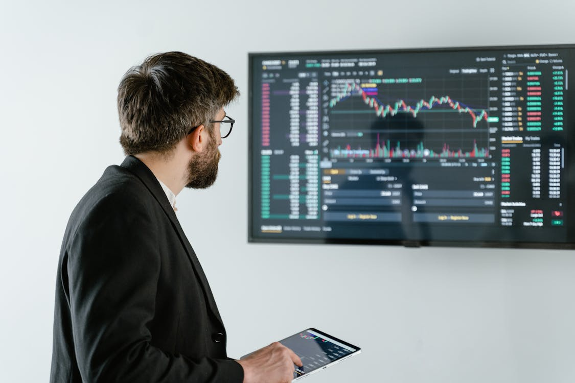 man in black suit jacket holding iPad.