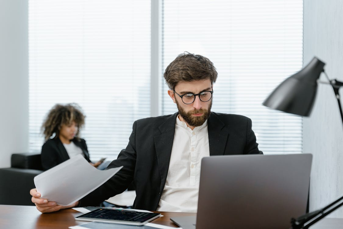 man in black suit jacket holding iPad.