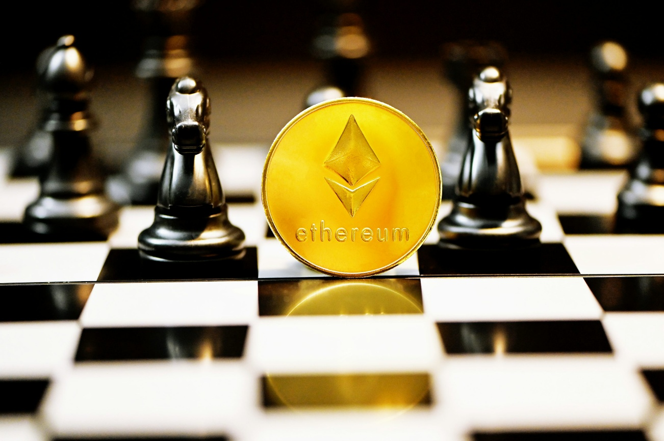Ethereum coin standing on a chessboard with black chess pieces in the background