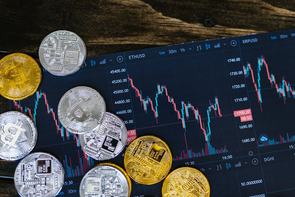 A close-up image of shiny silver and gold cryptocurrency coins placed on a dark surface.