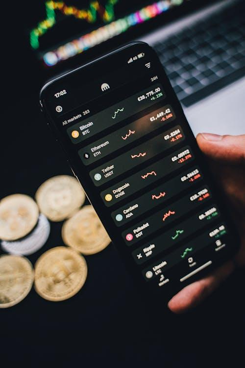 A hand holding a smartphone showing a cryptocurrency trading chart.