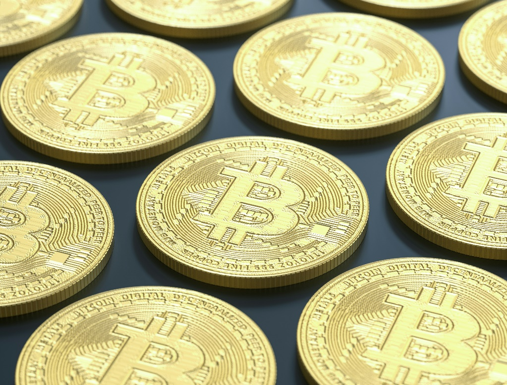 A high-angle, close-up shot of multiple golden Bitcoin cryptocurrency coins.