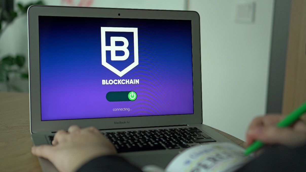 Hand accessing digital ledger on a computer, symbolizing permissioned access