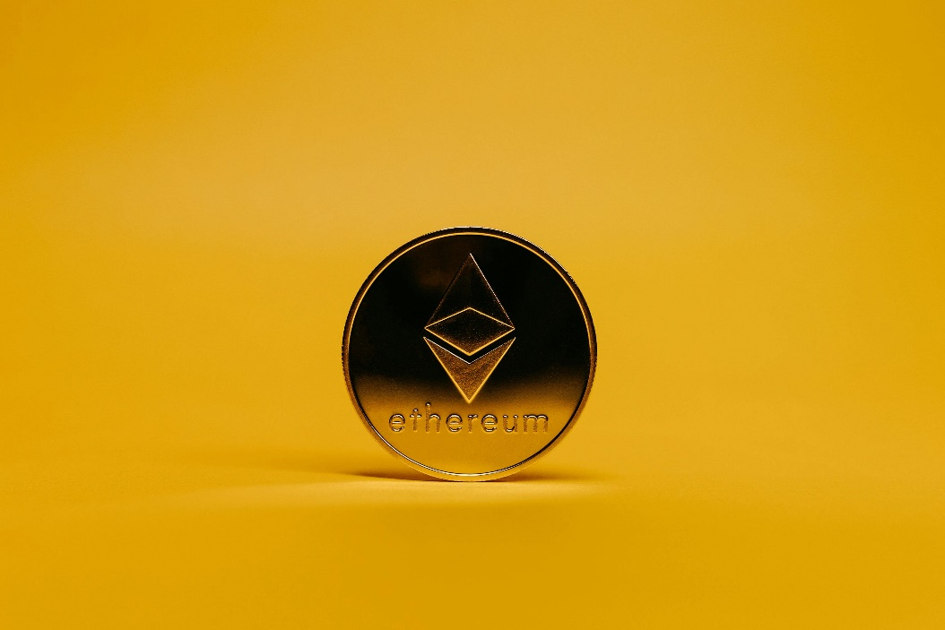 A single, golden Ethereum cryptocurrency coin standing upright.