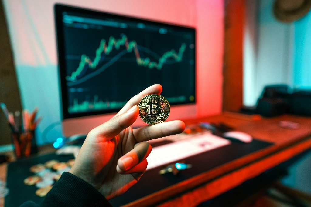 Hand holding a coin in front of a digital dashboard.