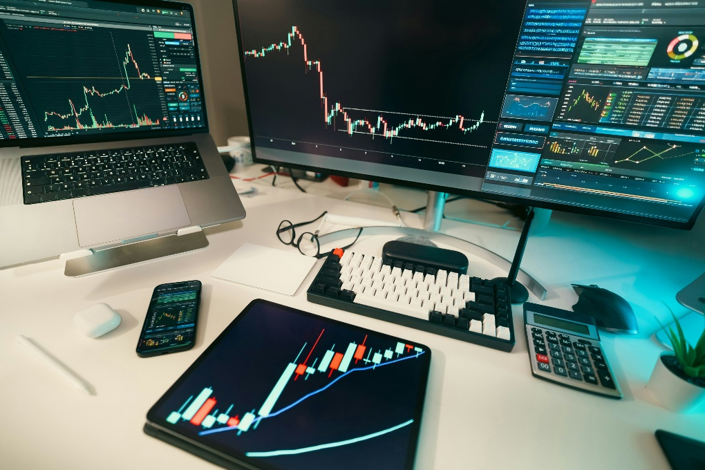 Multi-screen digital asset trading workstation displaying cryptocurrency charts, analytics dashboards, and candlestick market data across monitors.